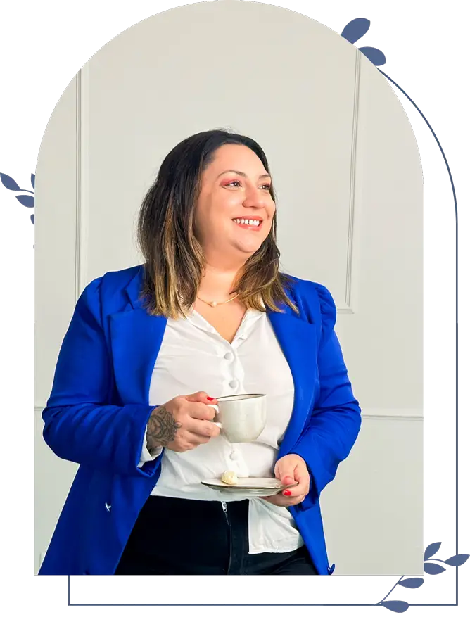 Mariana Rotta Psicóloga sorrindo com xícara na mão, vestindo blazer azul.