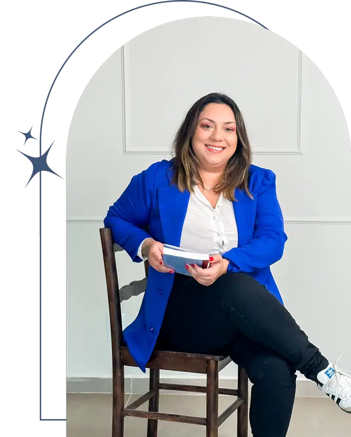 Mariana Rotta Psicóloga sentada com livro nas mãos e sorriso acolhedor no rosto.
